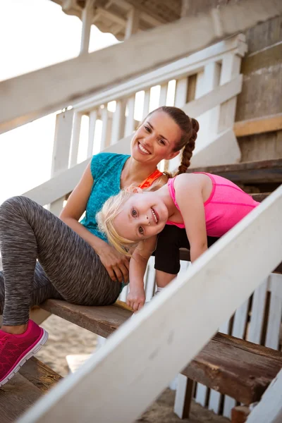 Здорова мати і дівчинка сидять на сходах пляжного будинку — стокове фото