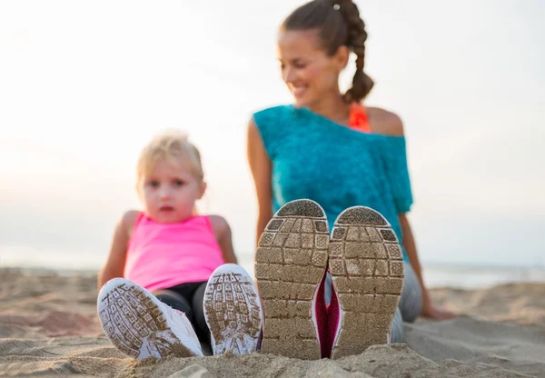 Nahaufnahme an den Beinen von Fitness-Mutter und Baby-Mädchen am Strand — Stockfoto