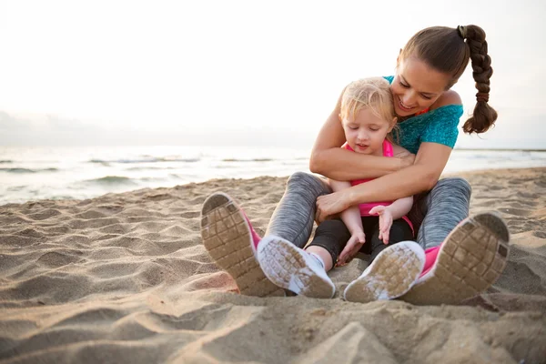 Madre sana y niña abrazándose en la playa por la noche — Foto de Stock