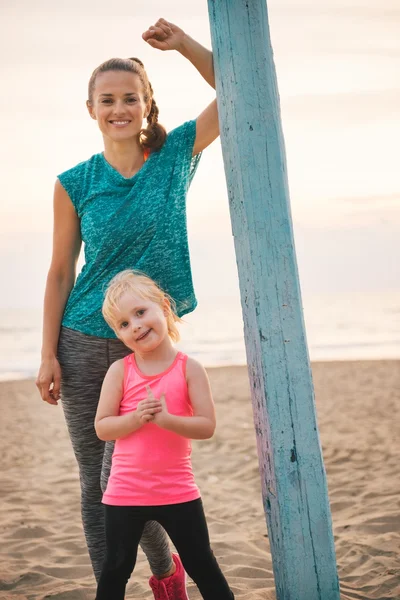 Porträt einer gesunden Mutter und eines kleinen Mädchens am Abend am Strand — Stockfoto