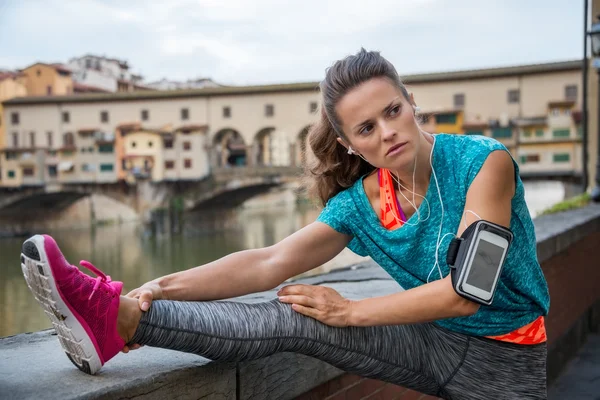 Fitness kvinde strækker nær ponte vecchio i florence, kursiv - Stock-foto