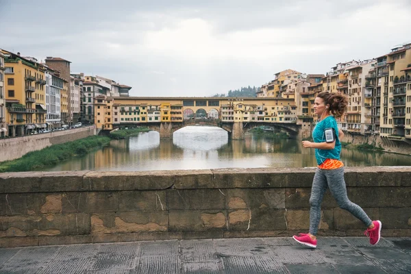 Fitness vrouw joggen voor ponte vecchio in florence, ita — Stockfoto