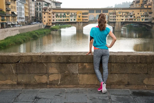 Mulher fitness olhando para ponte vecchio em florence, itália. retaguarda — Fotografia de Stock