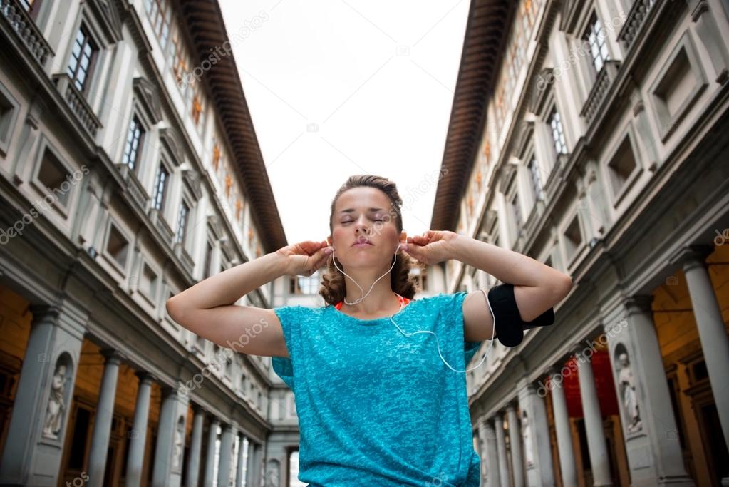 Fitness woman wearing earphones near uffizi gallery in florence,