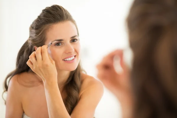幸せな若い女性の浴室で眉毛を整形 — ストック写真