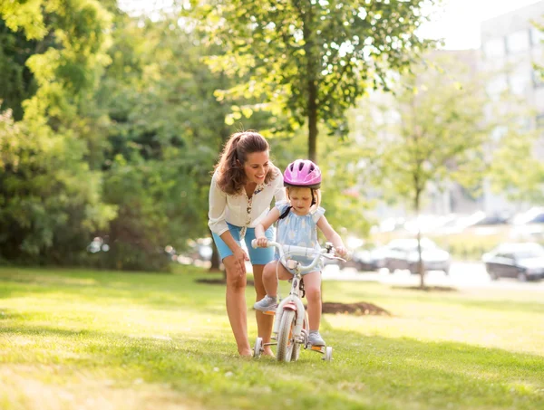 공원에서 자전거를 타고 하는 방법을 그녀의 딸을 교육 하는 어머니 — 스톡 사진