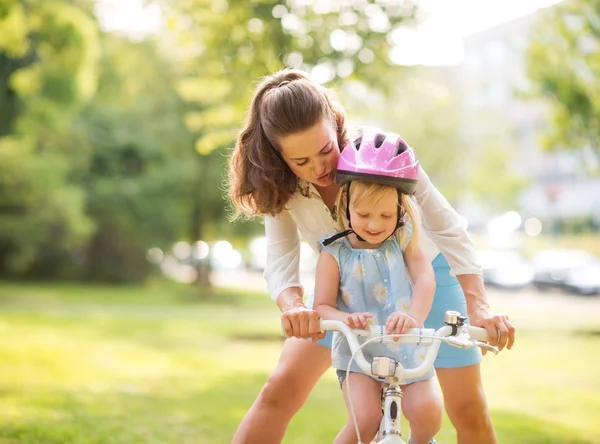Mère montre à sa fille comment monter sur un vélo tenant le guidon — Photo