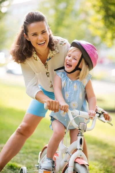 Rindo mãe e filha aprendendo a andar de bicicleta — Fotografia de Stock