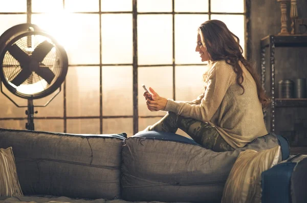 Profilo foto di donna seduta sul divano indietro sms sul telefono — Foto Stock