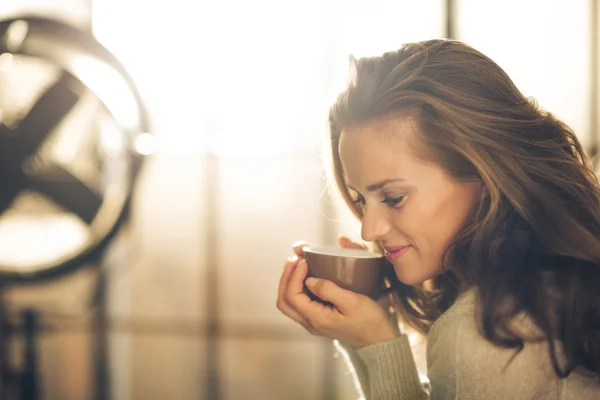 Nahaufnahme einer lächelnden Brünetten, die heißen Kaffee hält und riecht — Stockfoto