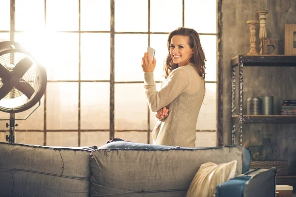 En regardant en arrière, une brune sourit debout près d'une fenêtre du loft — Photo