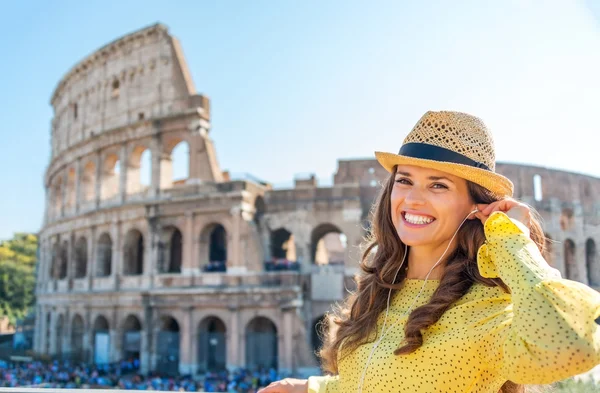 Woman standing near Colosseum in Rome adjusting earbud — Stock Photo, Image