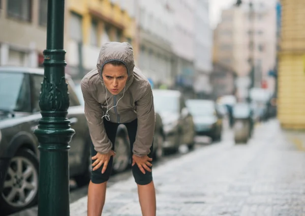 Nő runner az esőben, bevétel egy alkalom és nyújtás — Stock Fotó