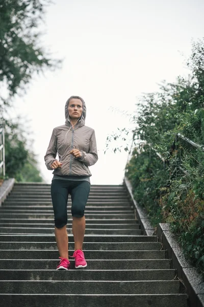 Woman jogger running down steps listening to music — Stock Photo, Image