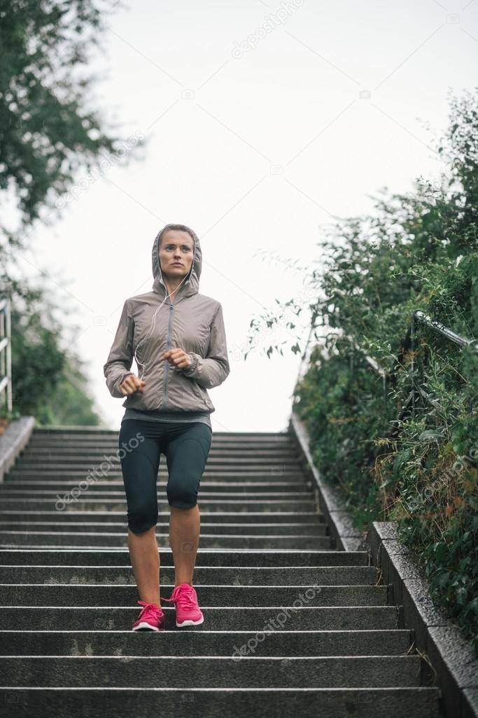 Woman jogger running down steps listening to music