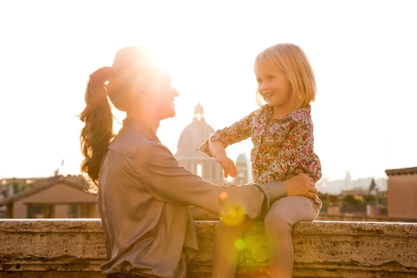 Mother holding daughter sitting on ledge in Rome — Stock Photo, Image