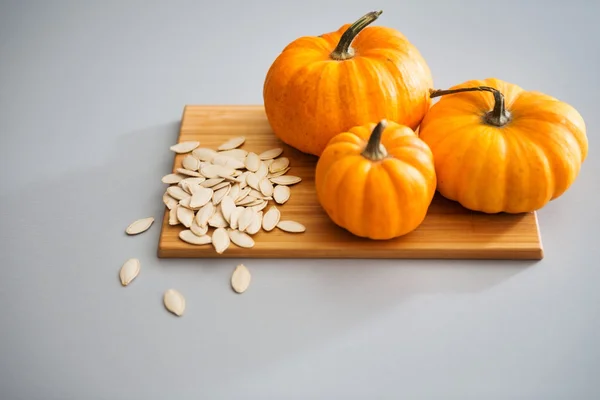 Gros plan de citrouilles miniatures et de graines sur une planche à découper — Photo