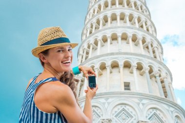 Smiling woman tourist taking photo of Leaning Tower of Pisa clipart