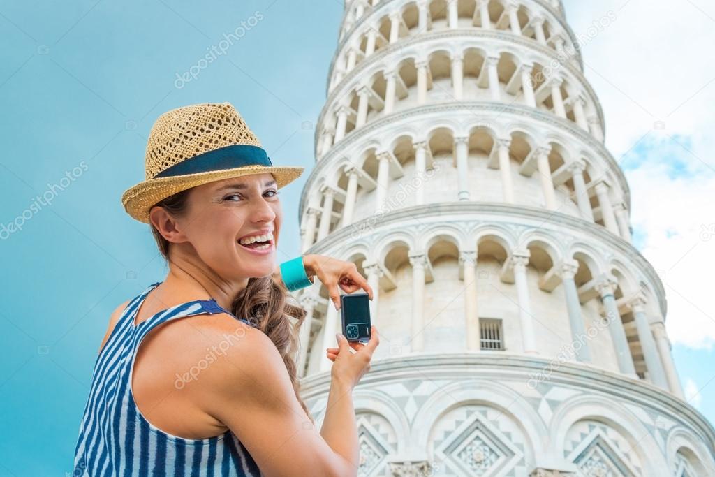 Smiling woman tourist taking photo of Leaning Tower of Pisa