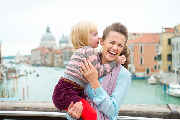 Lachende Mutter mit Tochter, die ihr ins Ohr flüstert — Stockfoto