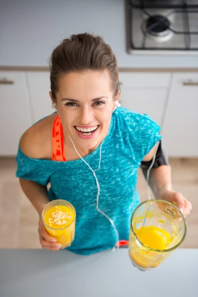 Atlético sorrindo mulher segurando smoothie recém-feito na cozinha — Fotografia de Stock