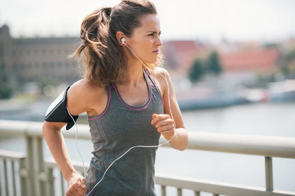 Jogging woman on bridge listening to music — Stock Photo, Image