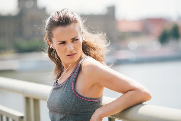 Woman jogger resting listening to music looking over shoulder — Stock Photo, Image