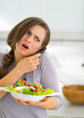 Cep telefonu konuşurken sebze salatası ile ilgili genç kadın