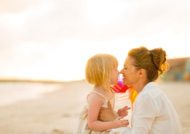 Mutlu anne ve bebek kız akşam plajda