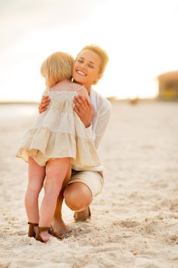 Akşam saatlerinde kumsalda sarılma anne ve bebek kız