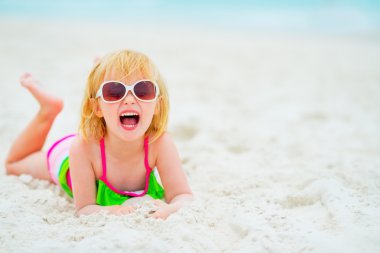 Kumsalda döşeme güneş gözlüklü kız mutlu bebek portresi