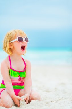 Mutlu bebek kız sahilde oturup güneş gözlüğü
