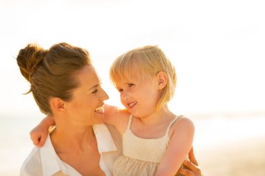 Mutlu anne ve bebek kız akşam plajda portresi