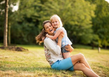 Mutlu anne ve bebek kız parkta sarılma portresi