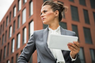 Serious business woman with tablet pc in front of office buildin