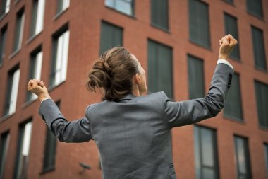 Business woman rejoicing in front of office building. rear view