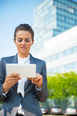 İş kadını ofis binasının önünde tablet bilgisayar kullanıyor
