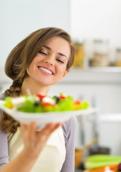 Ritratto di giovane casalinga felice che mostra insalata — Foto Stock