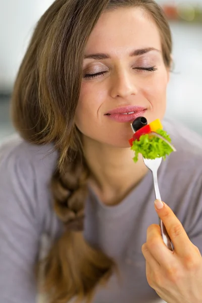 Porträt einer glücklichen jungen Hausfrau, die Gemüse isst — Stockfoto