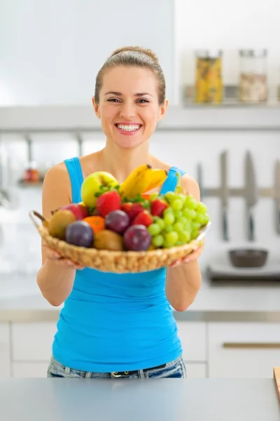 Sorrindo jovem mulher mostrando prato de frutas — Fotografia de Stock