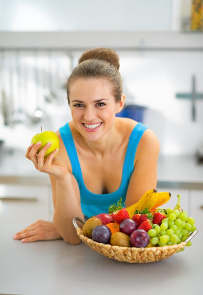 Happy young woman with fruits plate eating apple