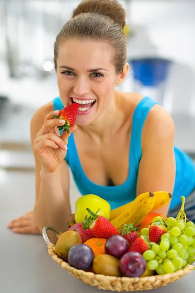 Крупный план молодой женщины с фруктовой тарелкой, поедающей клубнику — стоковое фото