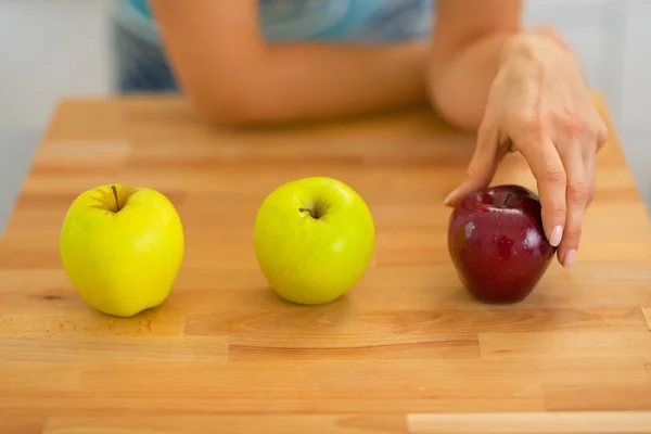 Closeup on young woman choosing between red and green apples — Stock Photo, Image