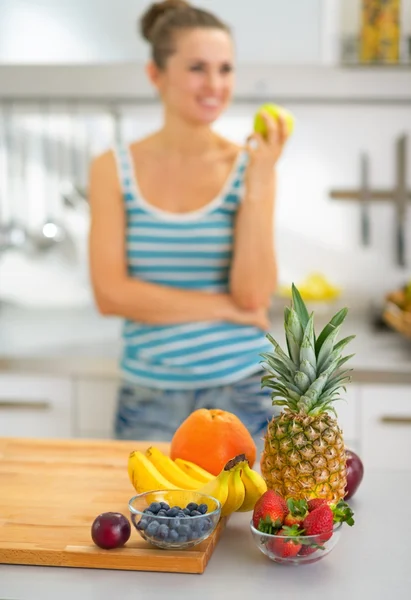 Nahaufnahme von Obst auf dem Tisch und junge Frau mit Apfel im Rücken — Stockfoto