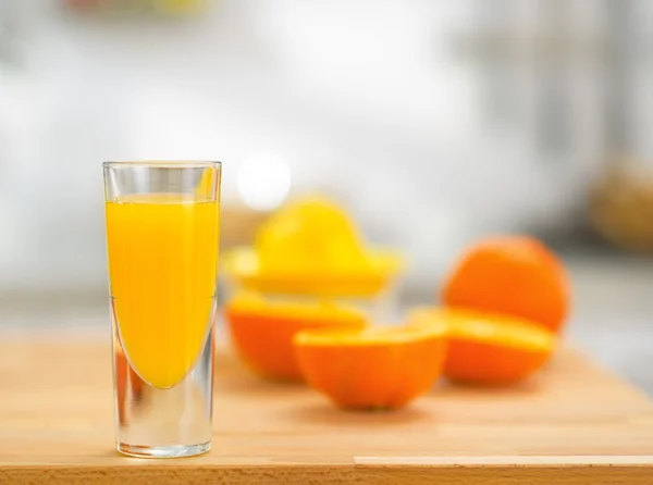 Closeup on glass of fresh orange juice and oranges on table — Stock Photo, Image