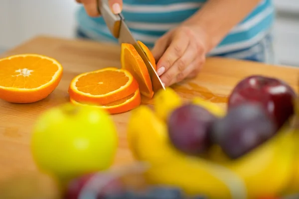 Gros plan sur jeune femme coupant orange — Photo