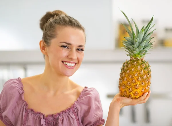 Portrét šťastná mladá hospodyňka ukazující ananas — Stock fotografie