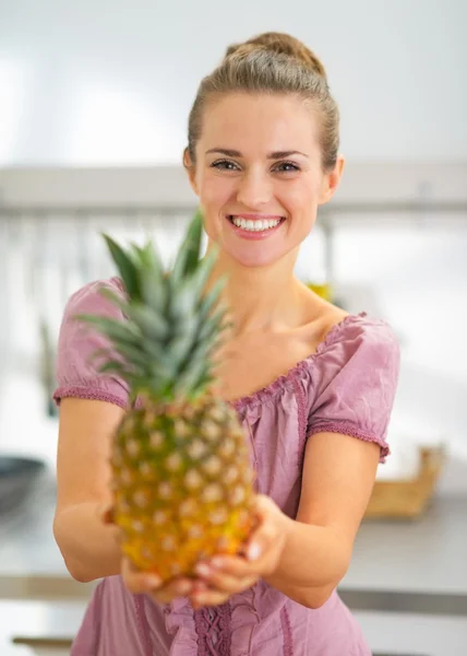 Portrait of happy young housewife showing pineapple — Stock Photo, Image