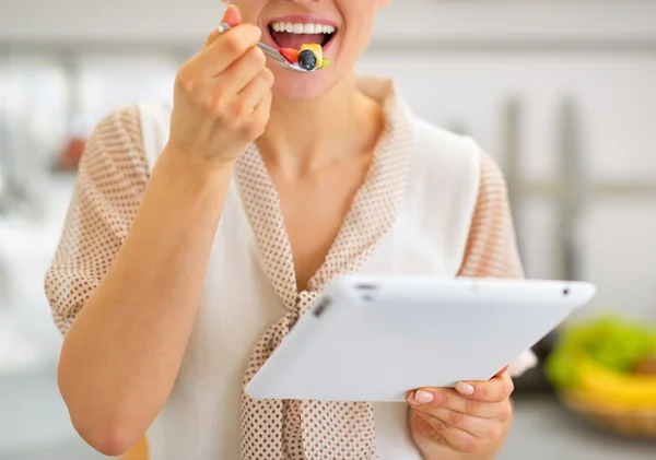 Primer plano de la mujer joven comiendo ensalada de frutas y el uso de tableta pc — Foto de Stock