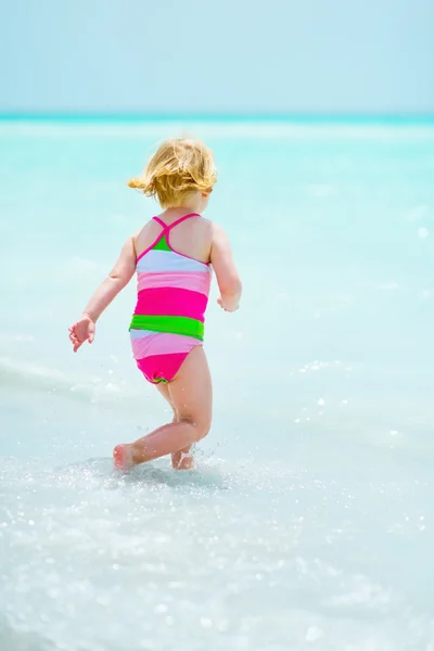 Baby girl playing on sea shore. rear view — Stock Photo, Image